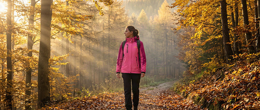 Randonnée en automne : randonneuse en veste imperméable sur un sentier forestier doré